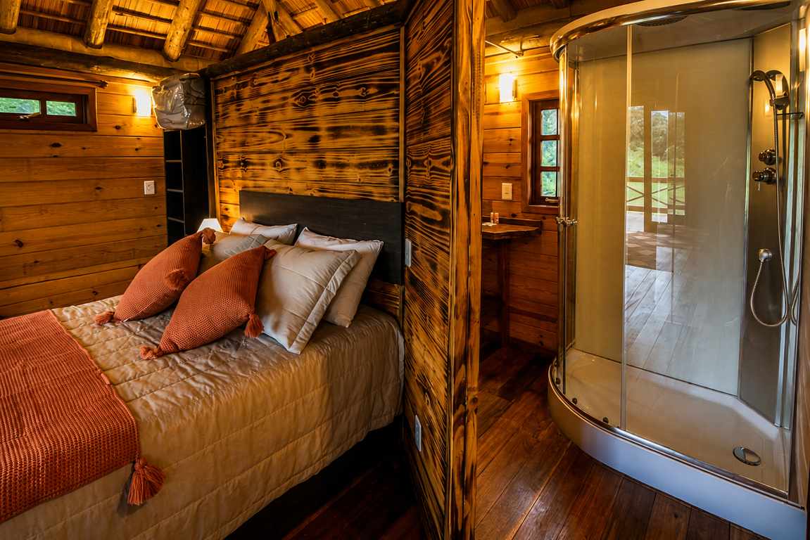 Warm cabin bedroom with timber walls and glass shower